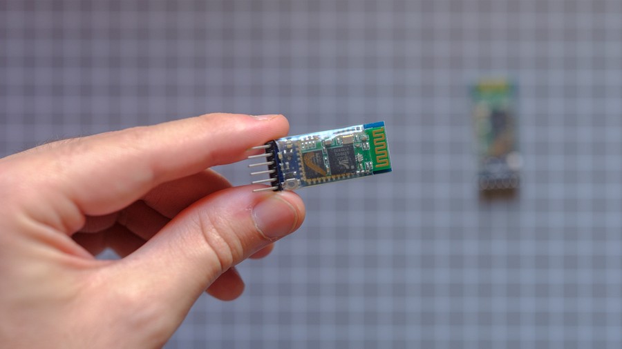 Hand holding single small blue and green RF module